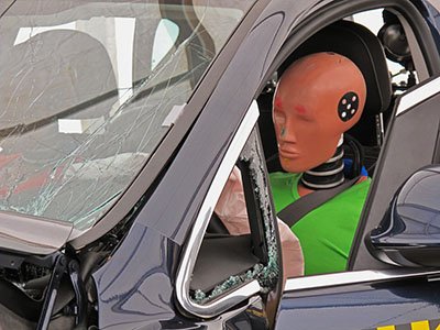 Driver's side view of a car with a crash dummy at the wheel Detail of a simulated car accident.