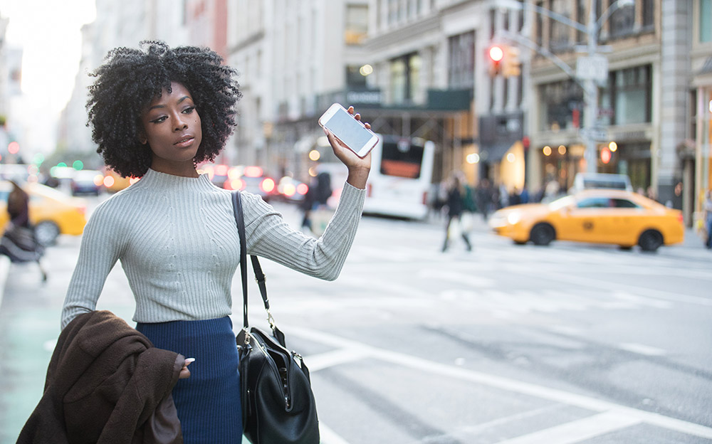 Woman with mobile device waiting for rideshare car service Woman with mobile device waiting for rideshare car service